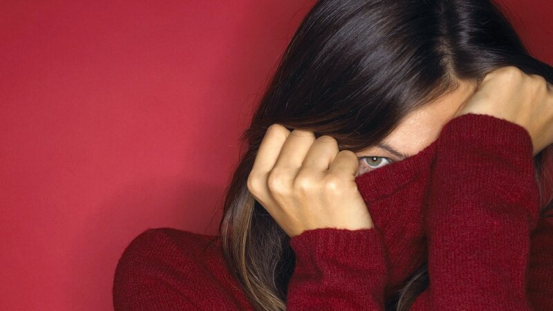 woman covering face with sweater