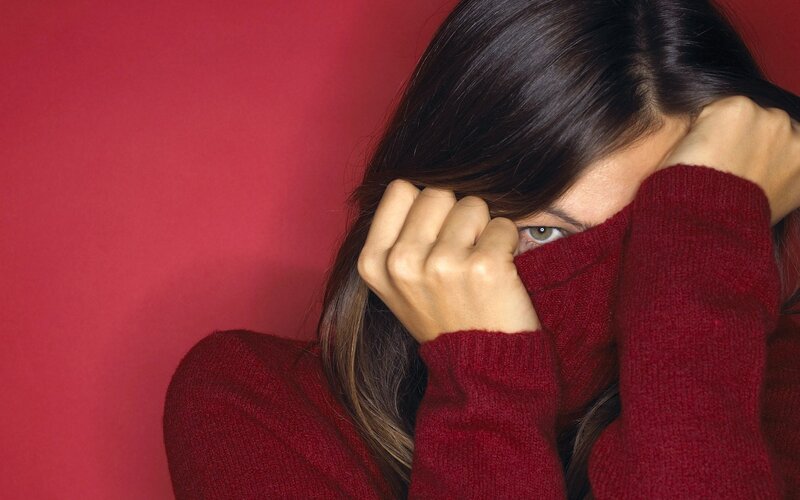 woman covering face with sweater