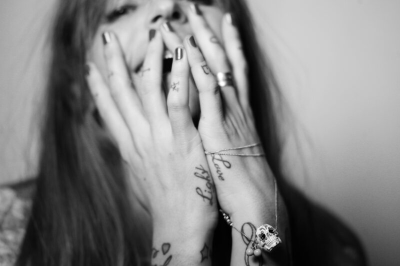 woman covering face with tattooed hands