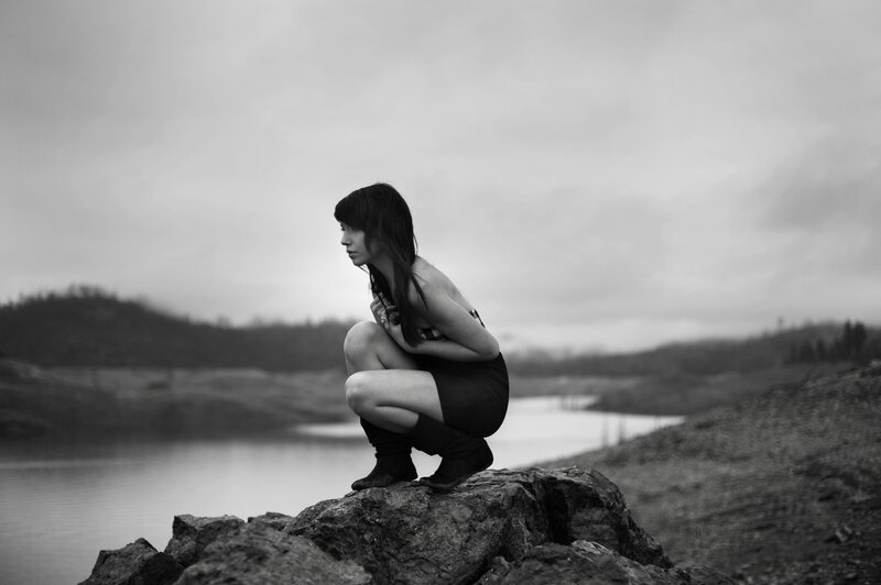 woman crouching by a lake