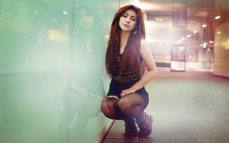 woman crouching by glass wall
