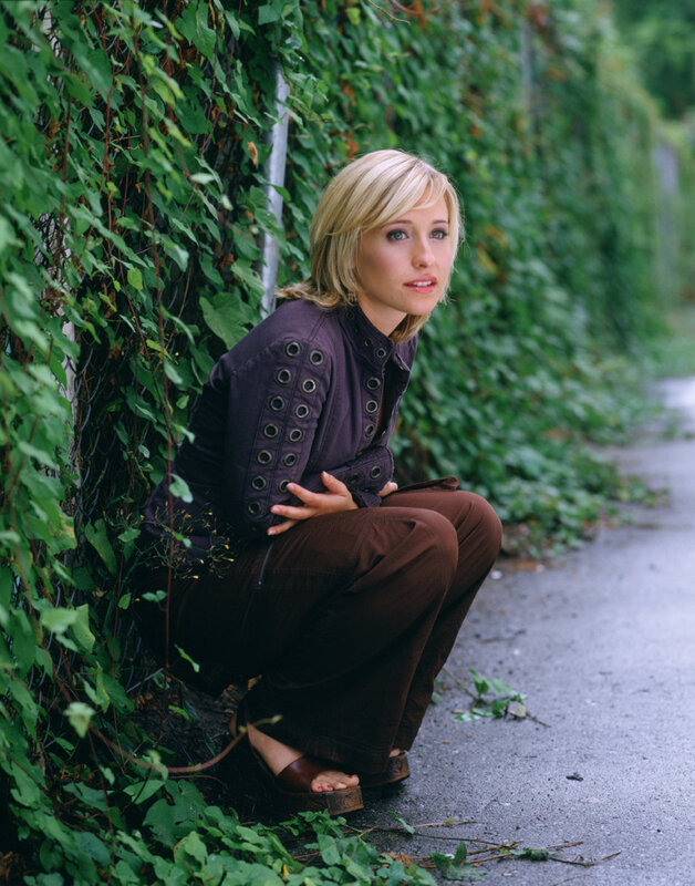 woman crouching by ivy wall