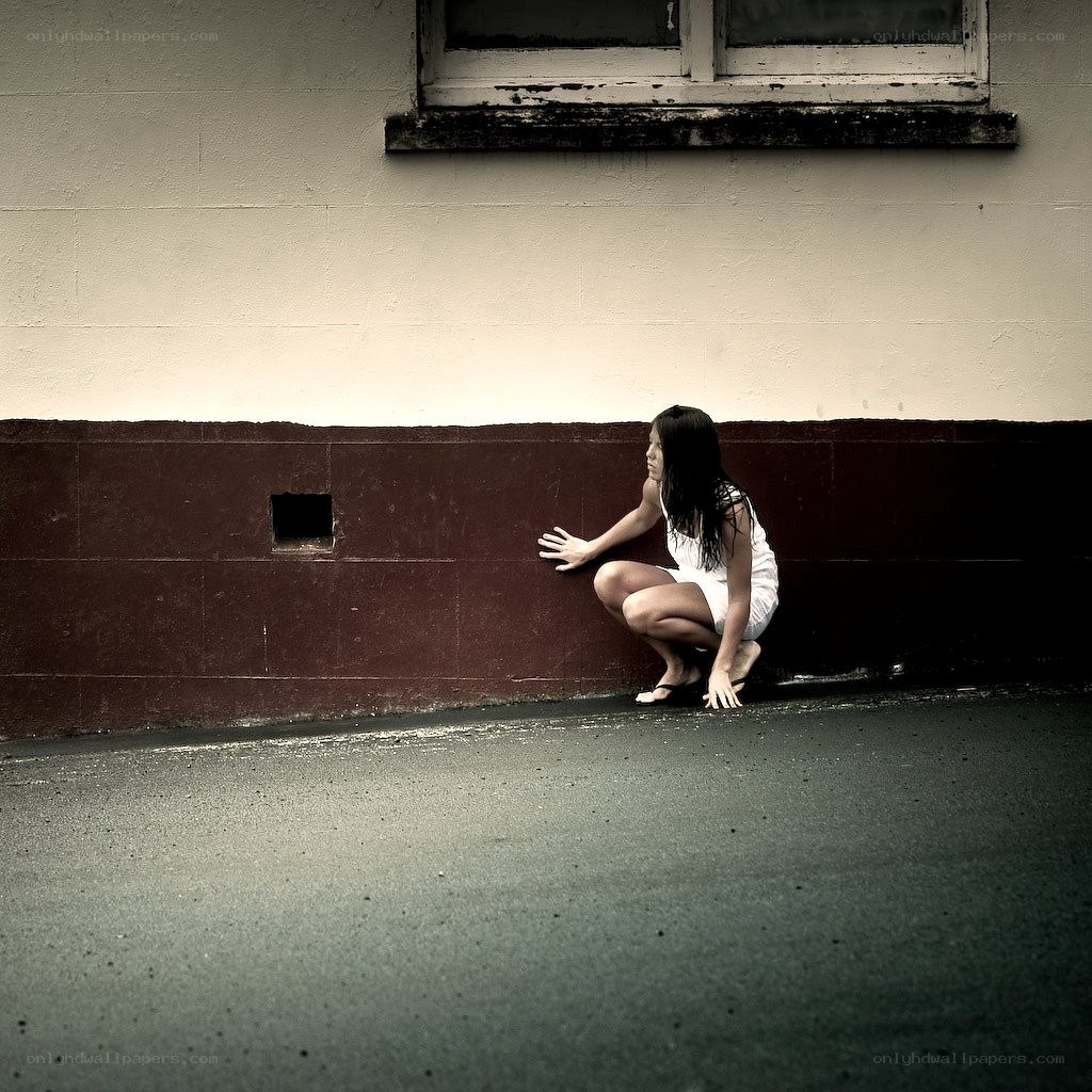 woman crouching by wall