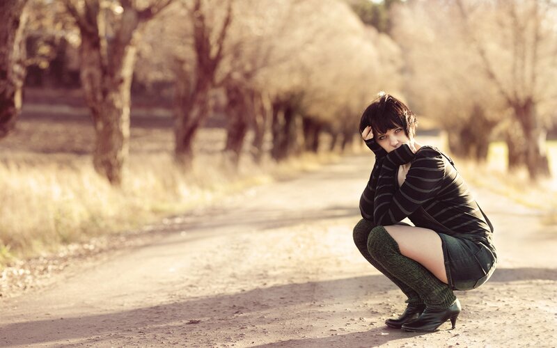 Woman crouching on a dirt road