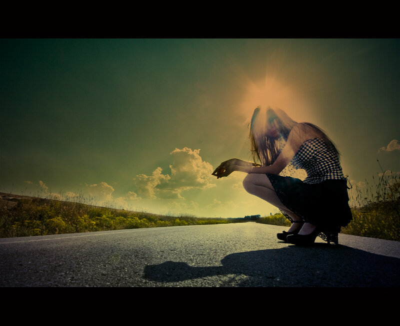 woman crouching on road at sunset