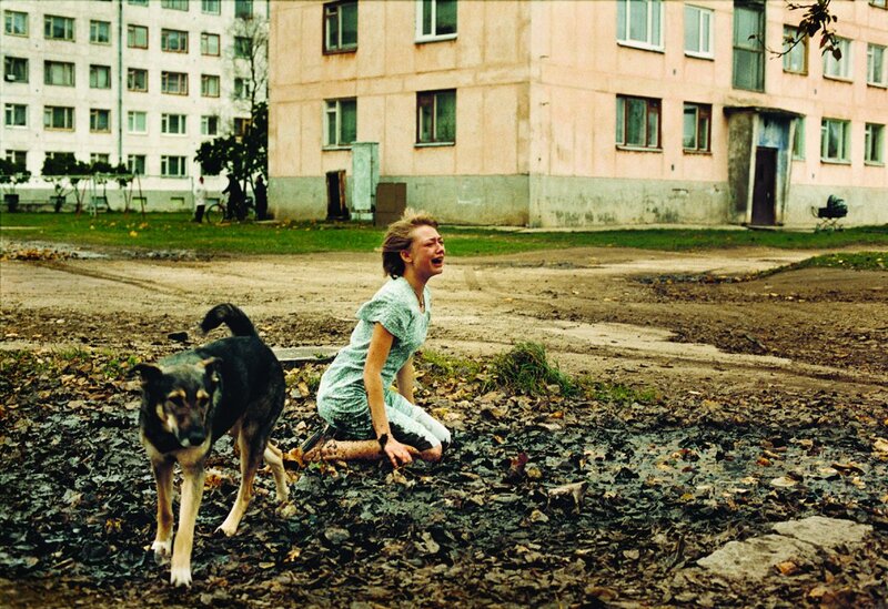 Woman crying with dog in courtyard