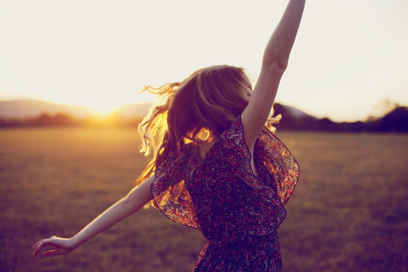 woman dancing in a field at sunset