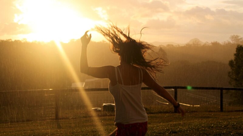 woman dancing in rain at sunset