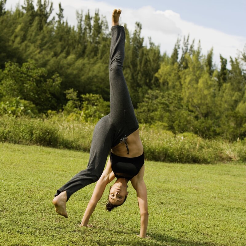 woman doing handstand in field