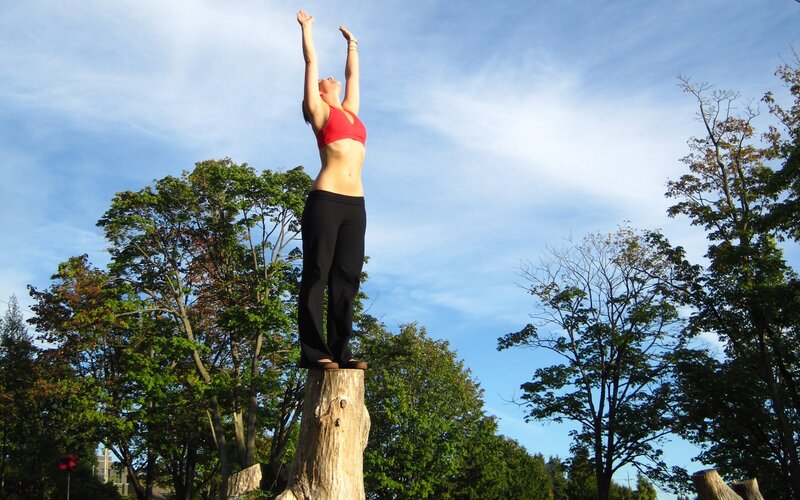 woman doing yoga on tree stump