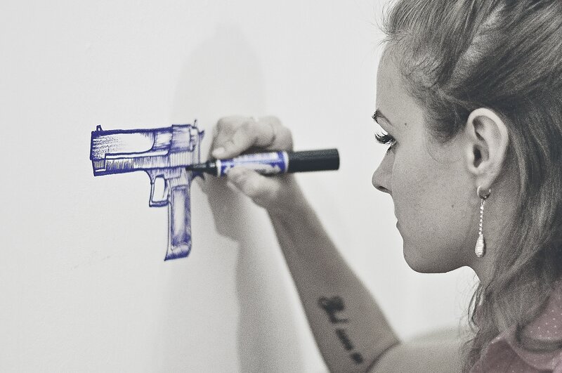 woman drawing gun on wall