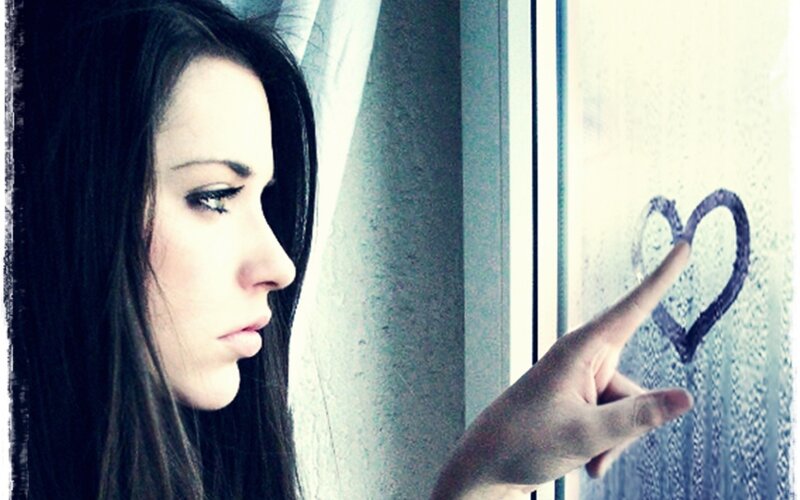 woman drawing heart on window
