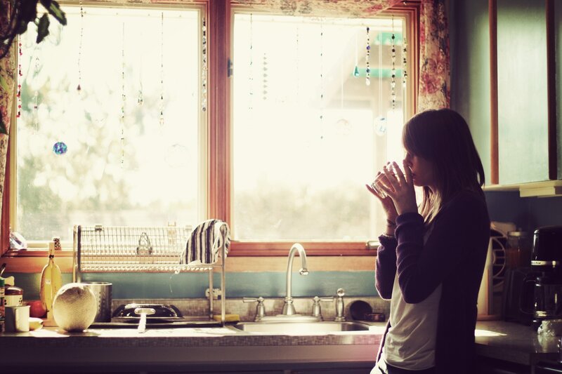 woman drinking by kitchen window