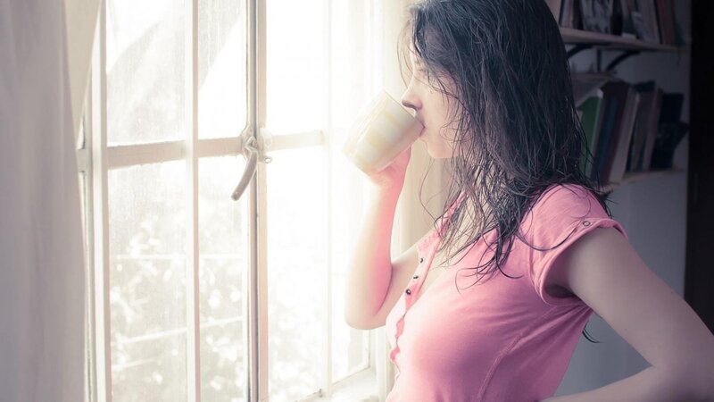 woman drinking by window