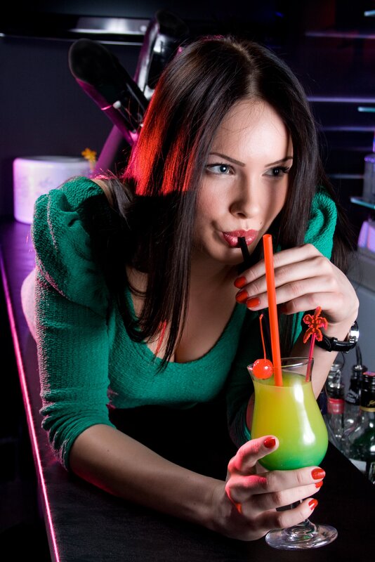 Woman drinking cocktail at bar