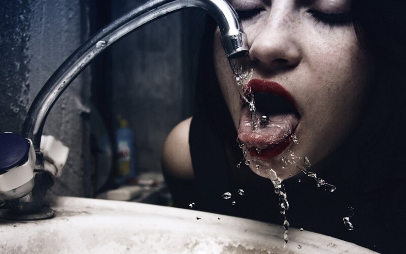 woman drinking water from faucet