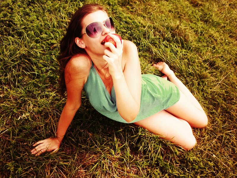 woman eating apple in grass