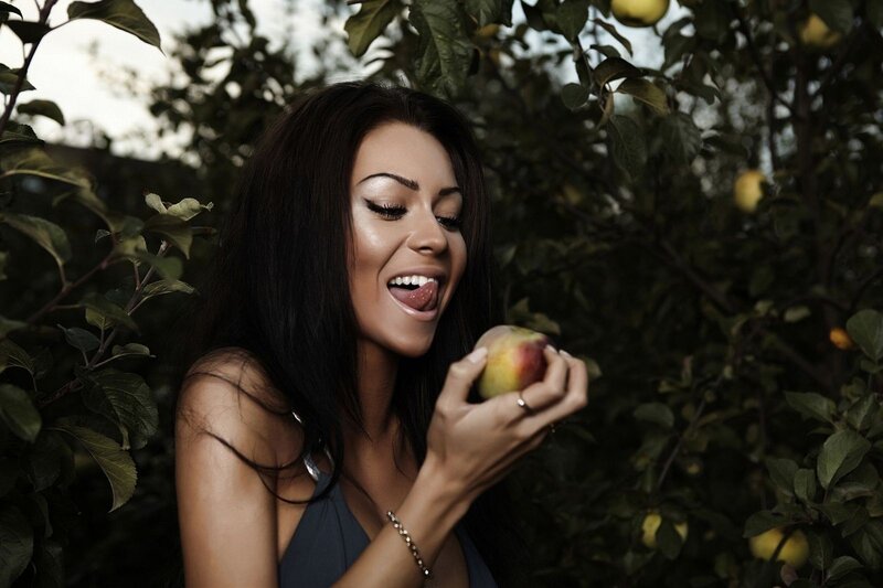 woman eating apple in orchard