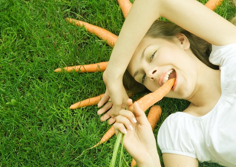 woman eating carrot on grass