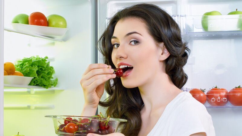 woman eating cherries in fridge