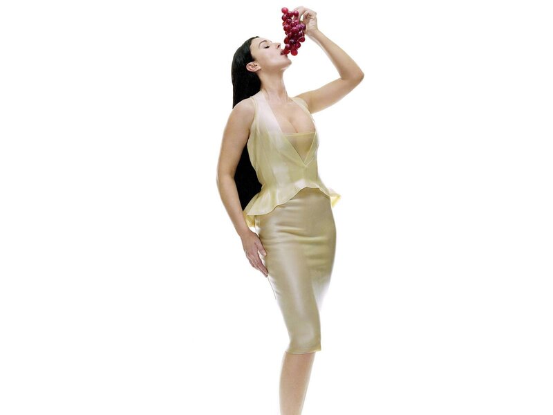 woman eating grapes in gold dress