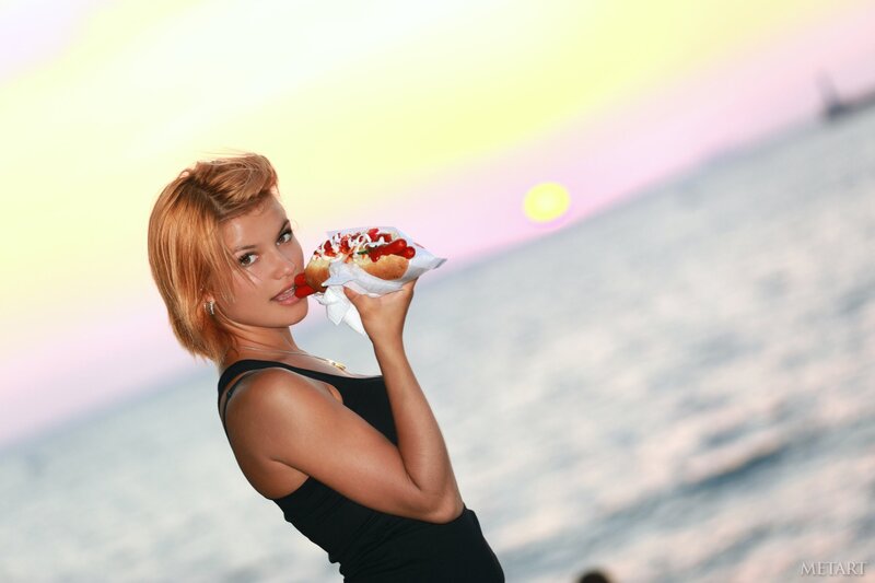 woman eating hot dog at sunset