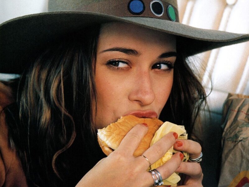 woman eating sandwich in hat