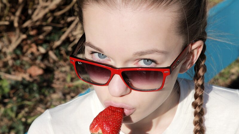 woman eating strawberry with sunglasses