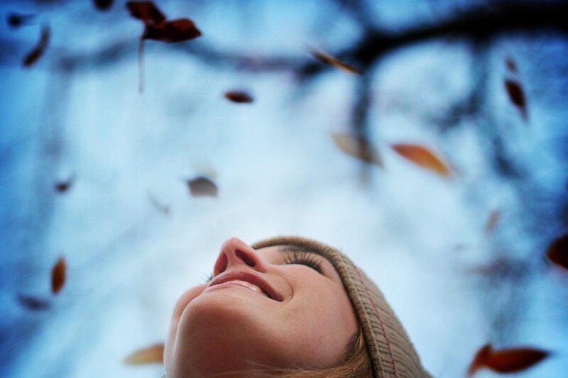 woman enjoying falling leaves