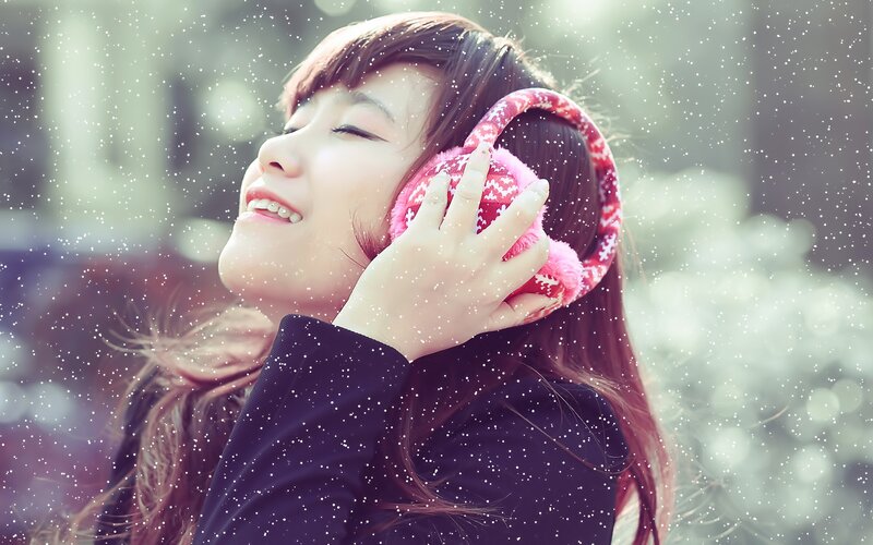 woman enjoying snowfall with earmuffs