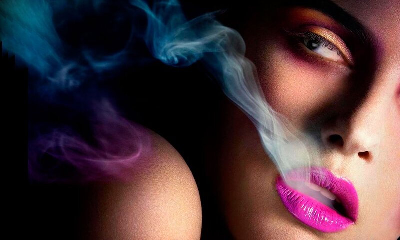 woman exhaling colorful smoke