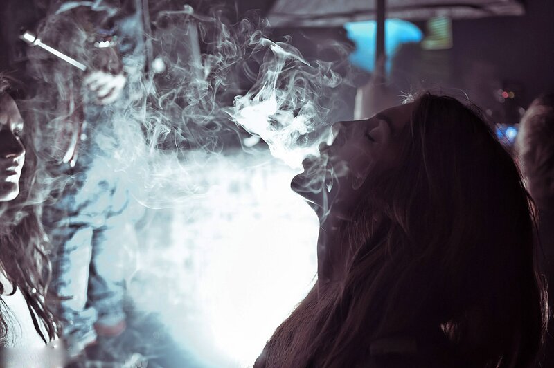 woman exhaling smoke in crowd