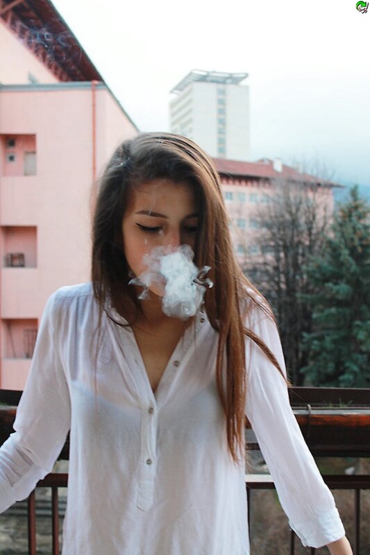 woman exhaling smoke on balcony