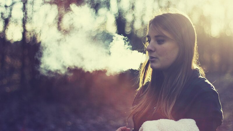 woman exhaling vapor in forest