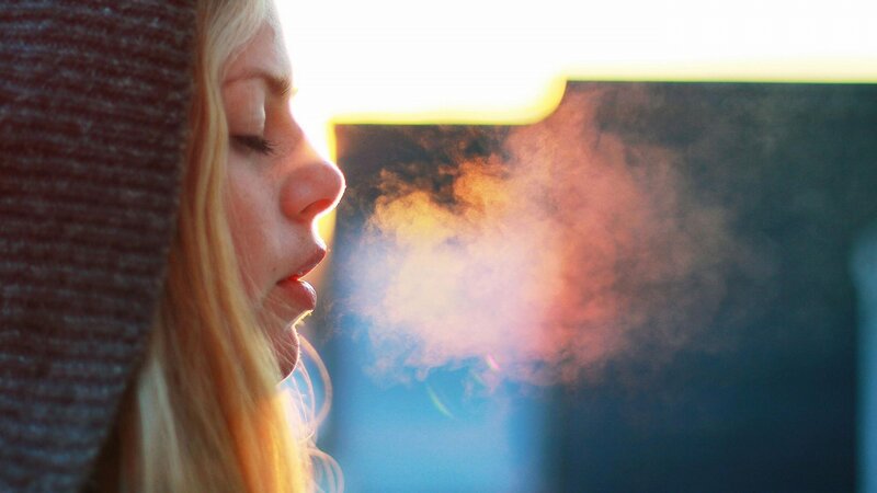 woman exhaling vapor in sunlight