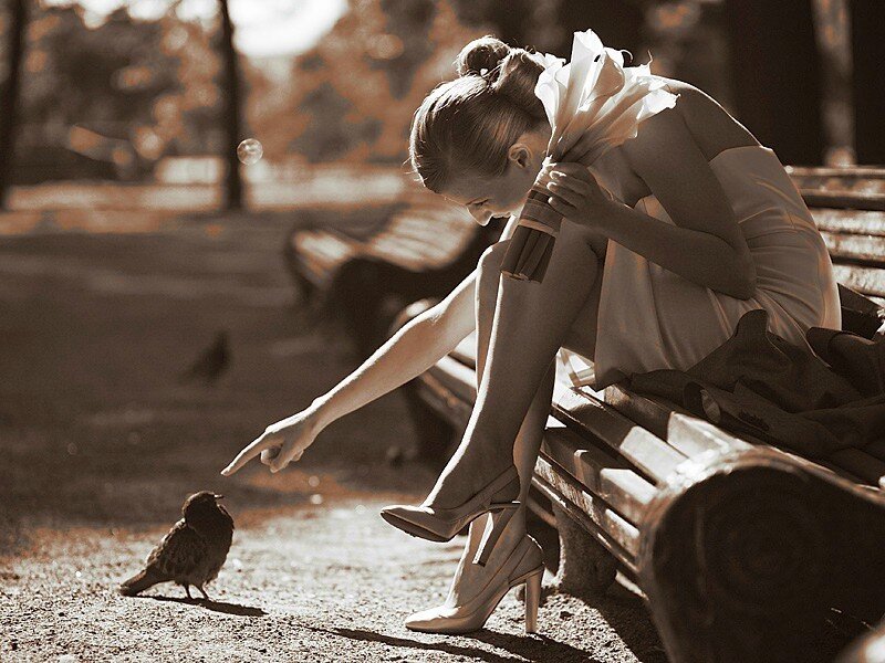 Woman feeding a bird on a bench