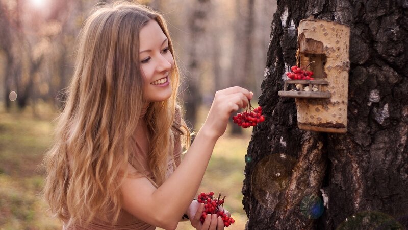 woman feeding birds in forest