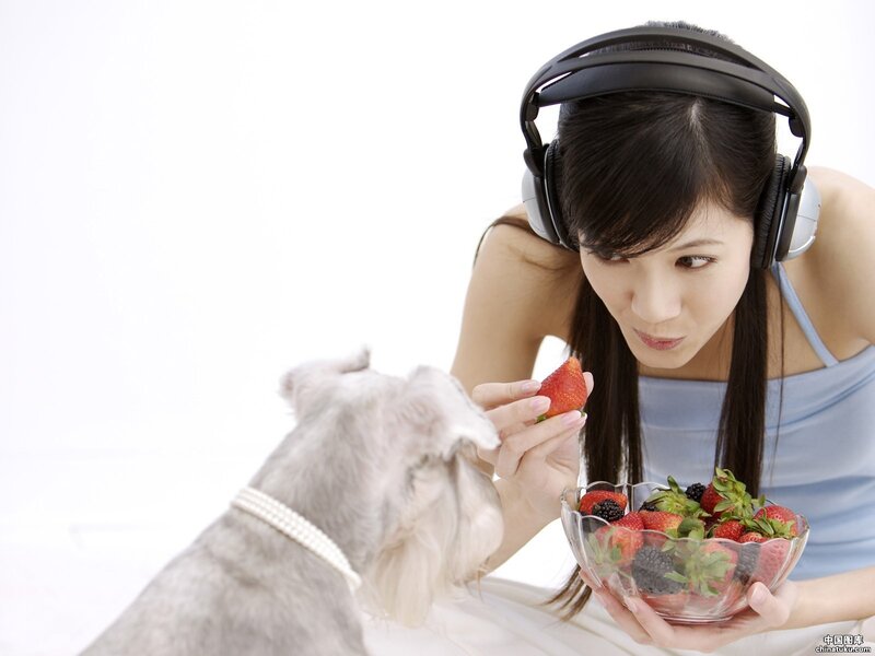 woman feeding strawberry to dog