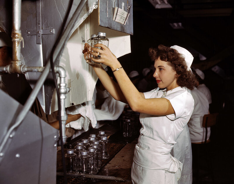 Woman filling glass bottles at factory