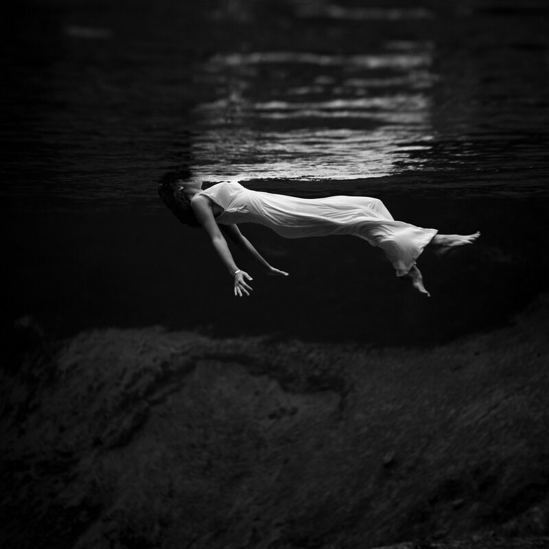 woman floating underwater in white dress