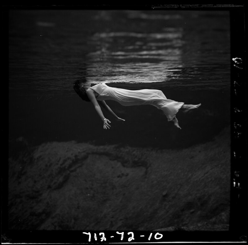 woman floating underwater in white dress