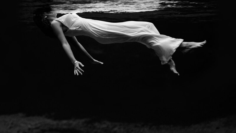 woman floating underwater in white dress