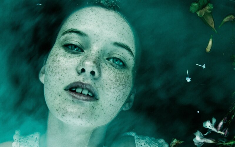 woman floating underwater with flowers