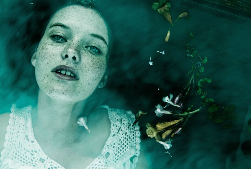 woman floating underwater with flowers