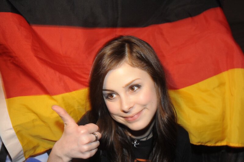 woman giving thumbs up in front of flag