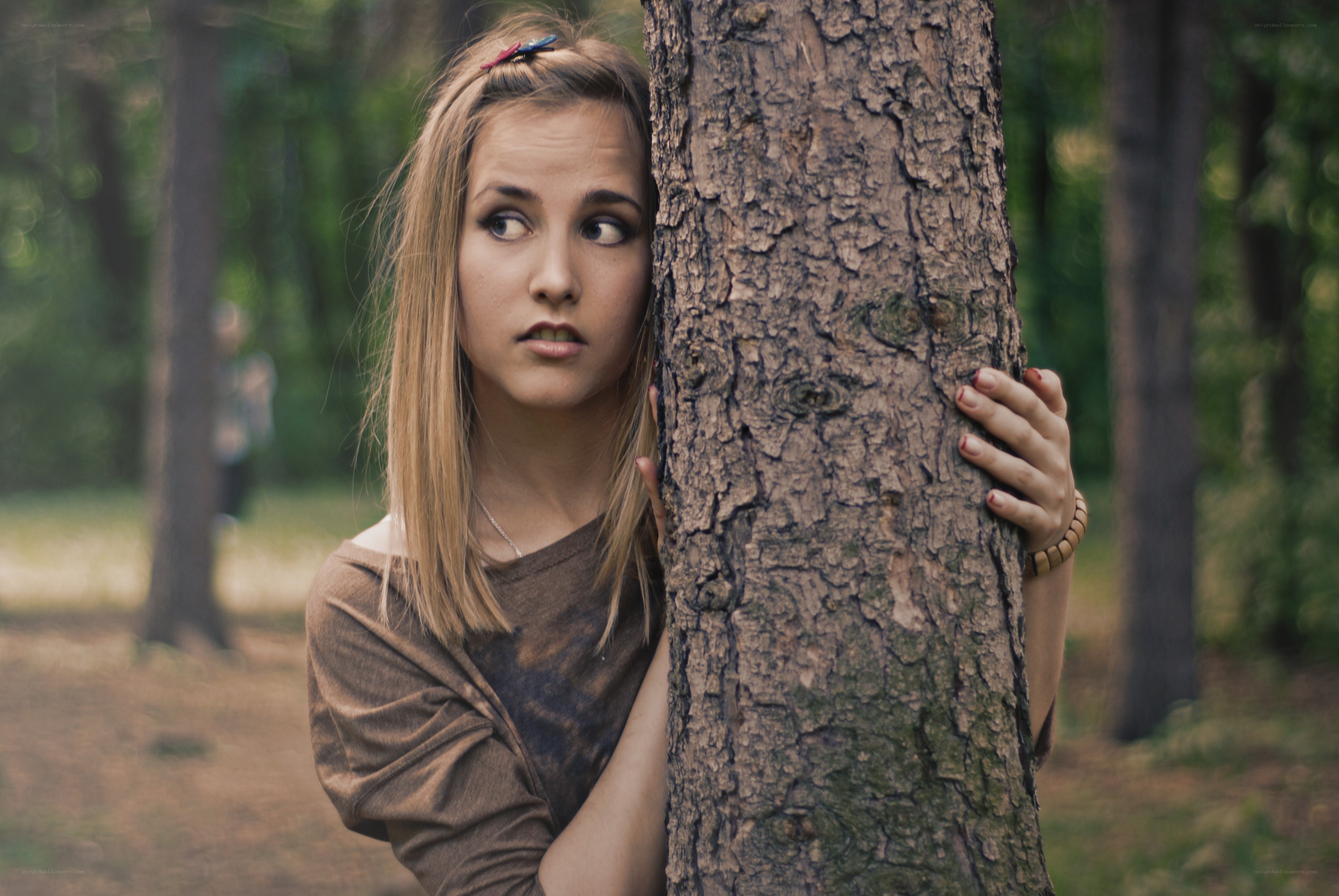 woman hiding behind a tree