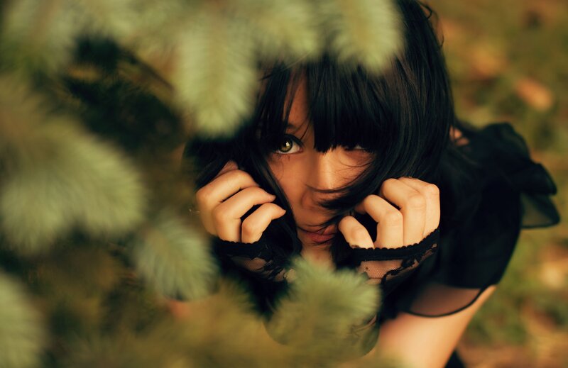 woman hiding behind foliage