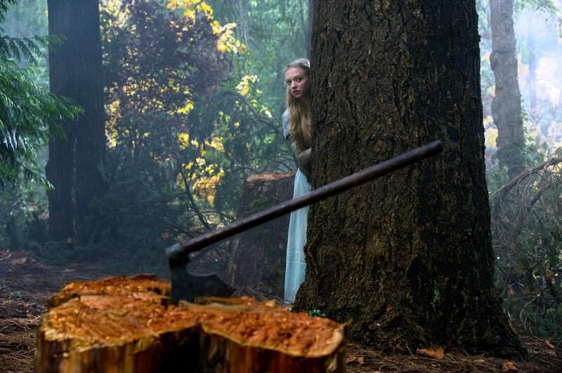 Woman hiding in forest with axe