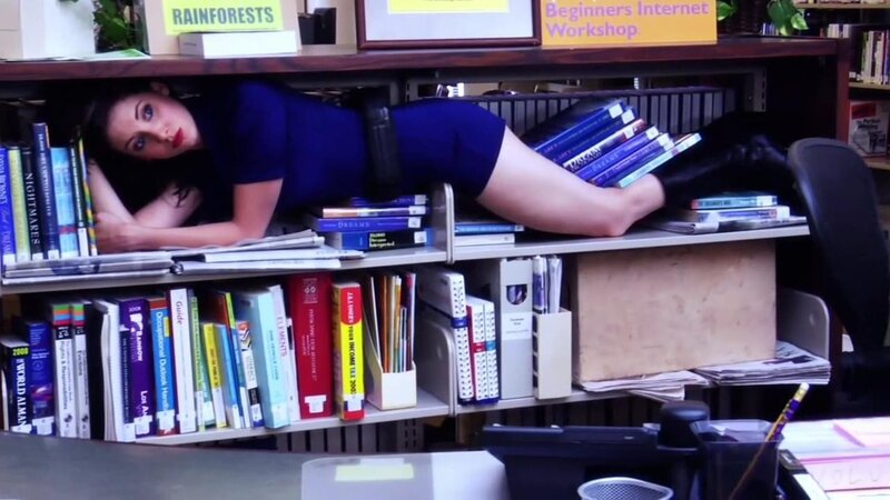 woman hiding under a bookshelf