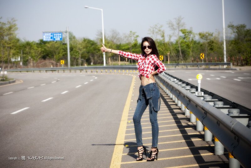 Woman hitchhiking on a road